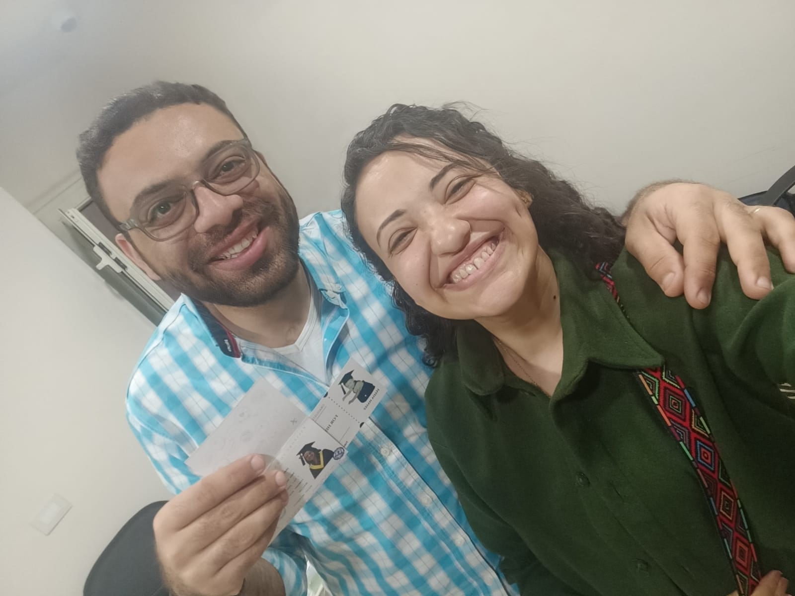 Nada and John laughing in a selfie, John holding a card